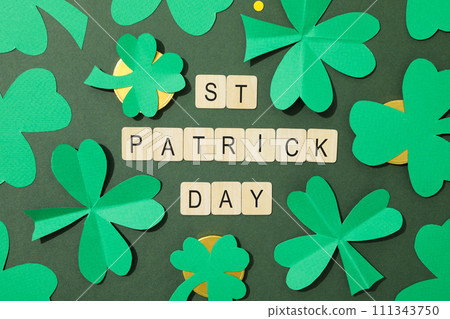 Paper clover leaves, golden coins and letters on green background, top view Paper clover leaves, golden coins and letters on green background, top view 111343750