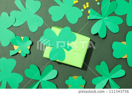 Paper clover leaves on golden coins and box on green background, top view 111343756