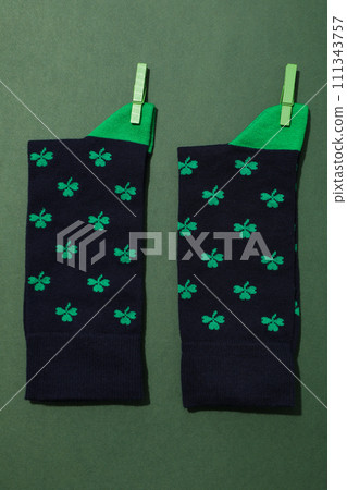 Dark socks with clover on green background, top view 111343757