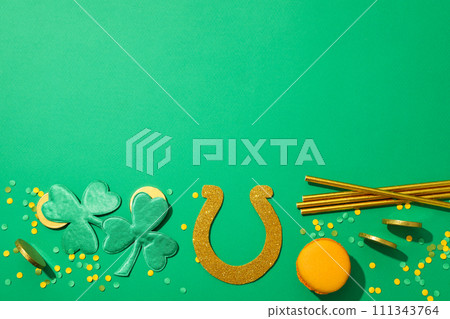 Clover, macaroons, gold coins and horseshoe on green background, space for text 111343764