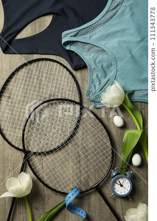 Sportswear and accessories, with flowers, on a wooden background. Sportswear and accessories, with flowers, on a wooden background. 111343778