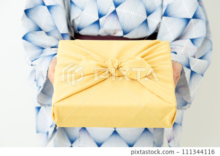 A middle-aged woman wearing a yukata holding a furoshiki wrapper as a summer gift A middle-aged woman wearing a yukata holding a furoshiki wrapper as a summer gift 111344116