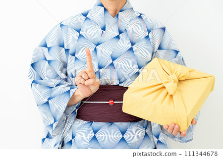 A middle-aged woman wearing a yukata and holding a wrapping cloth as a mid-year gift and raising her index finger A middle-aged woman wearing a yukata and holding a wrapping cloth as a mid-year gift and raising her index finger 111344678