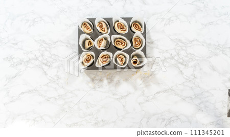 Flat lay. Filling cupcake liners with small cinnamon rolls to bake no-yeast cinnamon roll cupcakes. Flat lay. Filling cupcake liners with small cinnamon rolls to bake no-yeast cinnamon roll cupcakes. 111345201