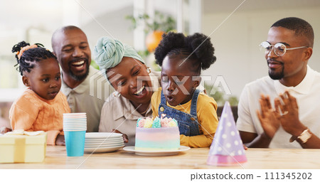 Birthday, children party and applause with a family in celebration of a girl child in their home. African parents, grandparents and kids clapping while blowing candles on a cake at a milestone event Birthday, children party and applause with a family in celebration of a girl child in their home. African parents, grandparents and kids clapping while blowing candles on a cake at a milestone event 111345202