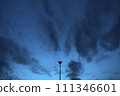 Evening cloudy sky with a single light pole. Lights off. Symmetry balanced in center.    111346601