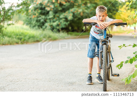 Tired boy resting by his bike after a long bike ride in the park 111346713