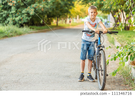 Tired boy resting by his bike after a long bike ride in the park Tired boy resting by his bike after a long bike ride in the park 111346716