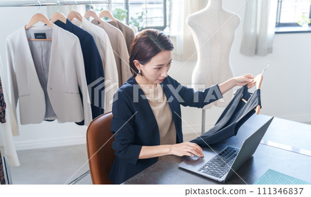 A woman checking clothes and entering data into a computer 111346837