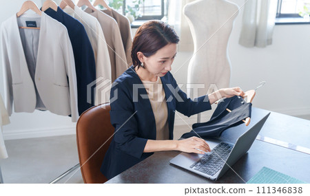 A woman checking clothes and entering data into a computer A woman checking clothes and entering data into a computer 111346838