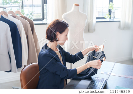 A woman checking clothes and entering data into a computer A woman checking clothes and entering data into a computer 111346839