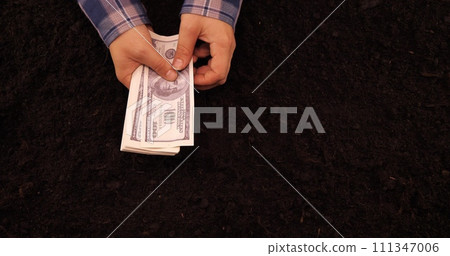 A farmer counts money in his hands against the background of soil The farmer calculates the income from the sale of the prepared crop Counting banknotes against the background of the earth, top view. A farmer counts money in his hands against the background of soil The farmer calculates the income from the sale of the prepared crop Counting banknotes against the background of the earth, top view. 111347006
