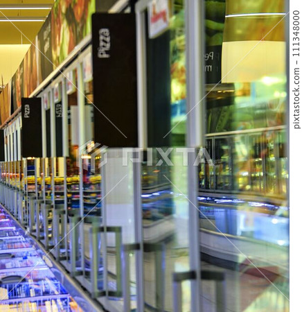 Blurred frozen food section at retail store in Europe. Freezer full assortment of frozen pizza in local supermarket, defocused background 111348000