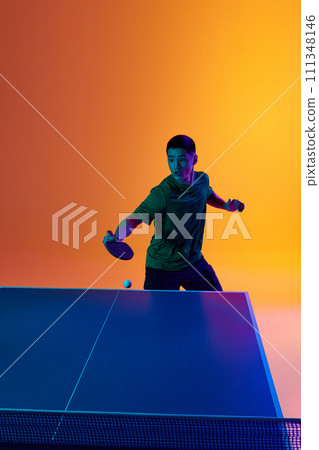 Portrait of confident and focused on game Asian table tennis player neon light against warm yellow gradient background. Dynamic gel portrait. Portrait of confident and focused on game Asian table tennis player neon light against warm yellow gradient background. Dynamic gel portrait. 111348146