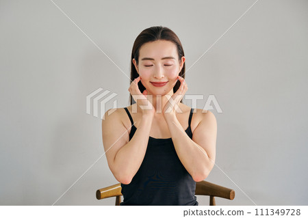 A woman in her 30s taking care of her skin by massaging her face A woman in her 30s taking care of her skin by massaging her face 111349728