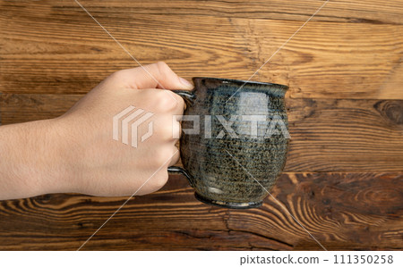 Hand Holds Cup, Empty Cup in Hands, Coffee Mug, Teacup Mockup, Cup in Arms on Wooden Table Hand Holds Cup, Empty Cup in Hands, Coffee Mug, Teacup Mockup, Cup in Arms on Wooden Table 111350258