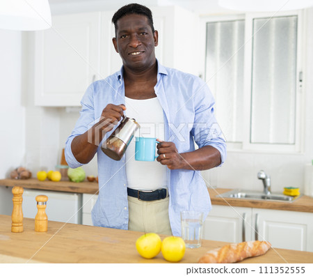 Relaxed adult man drinking coffee in morning in home kitchen 111352555