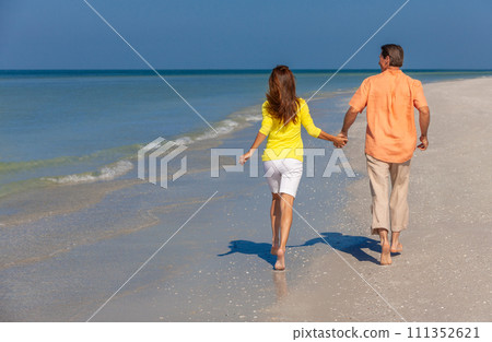 Rear View of Happy Couple Running Holding Hands on A Beach 111352621