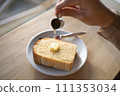 Hand applying honey to toast 111353034