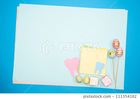 Greeting card for dentistry happy easter, space for text, tooth with painted eggs and gifts top view 111354102