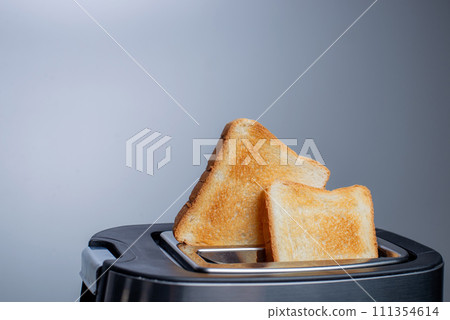 Modern toaster with crispy bread slices on white table Modern toaster with crispy bread slices on white table 111354614