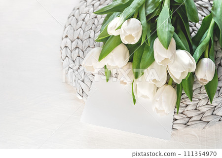 bouquet of fresh white tulips and blank card on Mothers day or Womens day. Top view with copy space Floral composition Romantic background 111354970