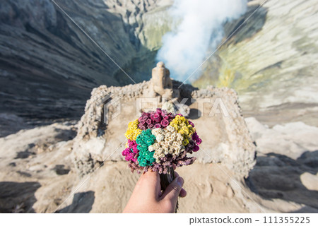 Cropped shot view of someone hand holding flowers for praying and offering to Ganesha statue the Hindu god located on Mt.Bromo crater in East Java of Indonesia. Cropped shot view of someone hand holding flowers for praying and offering to Ganesha statue the Hindu god located on Mt.Bromo crater in East Java of Indonesia. 111355225