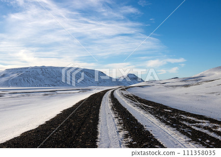 Gravel side road and a white snowy country, Iceland 111358035