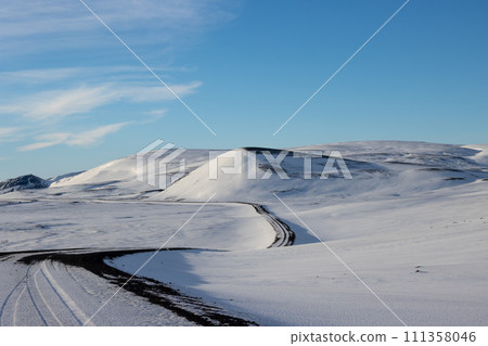 Gravel side road and a white snowy country, Iceland 111358046