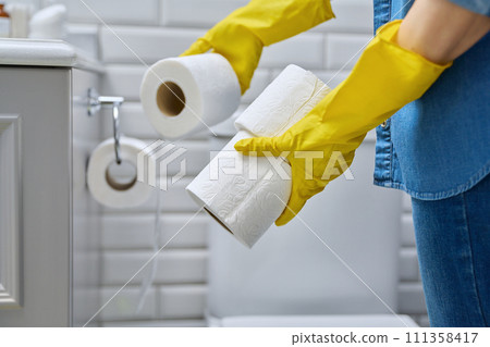Close-up of tubes of toilet paper in hands, toilet room interior Close-up of tubes of toilet paper in hands, toilet room interior 111358417