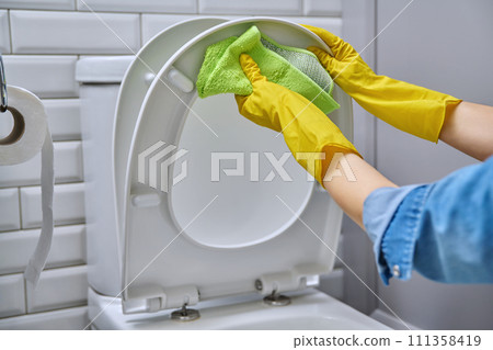 Close-up hands in protective gloves cleaning toilet in bathroom 111358419