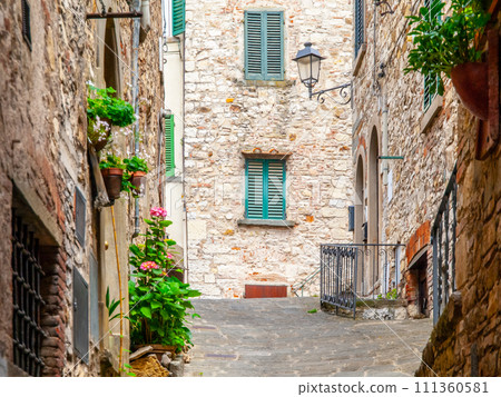 Old medieval street with flowers at stone houses in Tuscan town 111360581