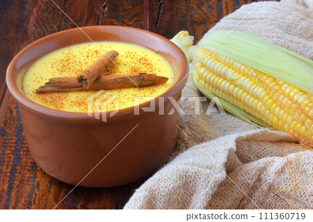 Curau, cream of corn sweet and dessert typical of the Brazilian cuisine, with cinnamon placed in ceramic bowl on wooden table. Copy space 111360719