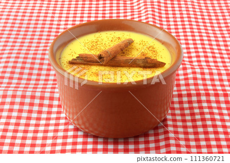 curau, cream of sweet corn and dessert typical of the Brazilian cuisine, with cinnamon placed in a ceramic bowl on a checkered tablecloth. 111360721