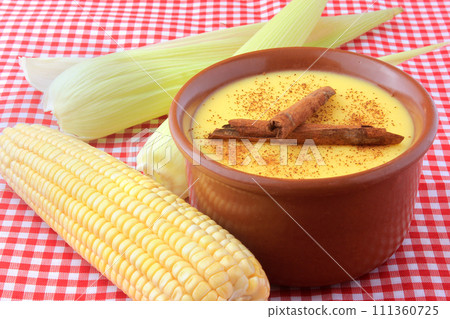 curau, cream of sweet corn and dessert typical of the Brazilian cuisine, with cinnamon placed in a ceramic bowl on a checkered tablecloth. 111360725