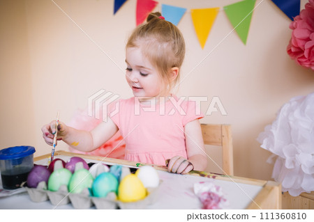 Cute girl painting Easter eggs in bright colourful room 111360810