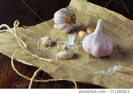 Garlic bulbs on packing paper, on rustic wooden table. Closeup garlic Garlic bulbs on packing paper, on rustic wooden table. Closeup garlic 111360821