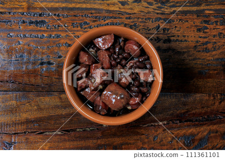 pot with feijoada, traditional brazilian cuisine dish, isolated under wooden background 111361101