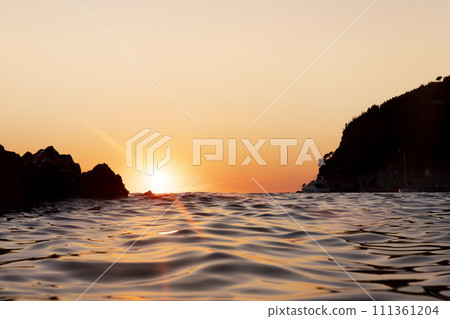 Sunset with yellow sun at the horizon at sea 111361204