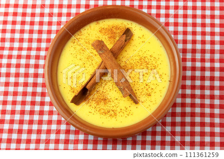 curau, cream of sweet corn and dessert typical of the Brazilian cuisine, with cinnamon placed in a ceramic bowl on a checkered tablecloth. 111361259