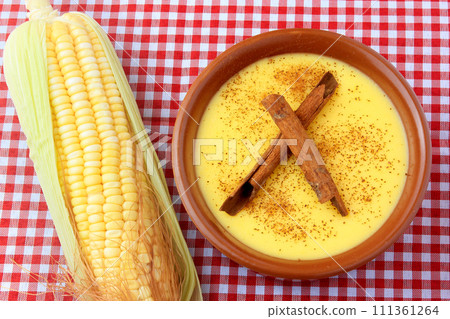 curau, cream of sweet corn and dessert typical of the Brazilian cuisine, with cinnamon placed in a ceramic bowl on a checkered tablecloth. 111361264