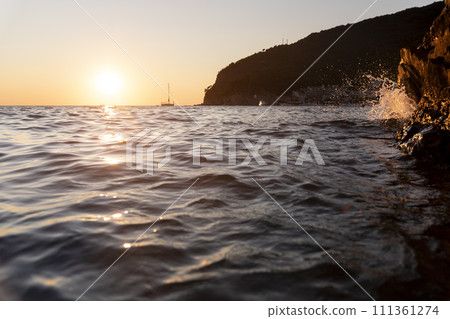 Sea water splashing at rocks at sunset 111361274