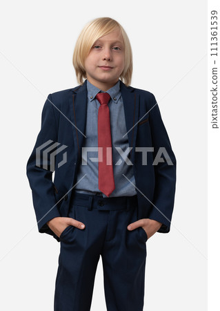 Portrait of a cute little boy in a suit stands and keeps hands in pockets. Isolated on white background 111361539