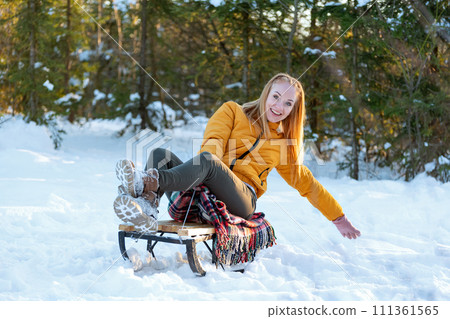 A young woman is riding a sledge in the winter forest. A young woman is riding a sledge in the winter forest. 111361565