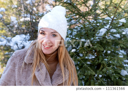 Winter portrait of red-haired girl in fur coat and white knitted hat with bubo on snow-covered fir trees background. Winter portrait of red-haired girl in fur coat and white knitted hat with bubo on snow-covered fir trees background. 111361566