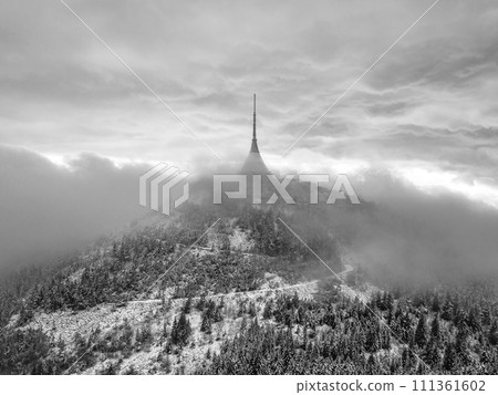 Jested mountain with modern hotel and TV transmitter on the top, Liberec, Czech Republic. Building in clouds. Aerial view from drone.. Black and white image. Jested mountain with modern hotel and TV transmitter on the top, Liberec, Czech Republic. Building in clouds. Aerial view from drone.. Black and white image. 111361602
