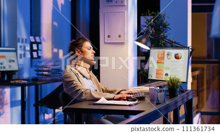 Businesswoman wearing cervical neck collar in office, analyzing diagrams to create financial report. Injured corporate worker planning analytics typing data late at night in company office. 111361734