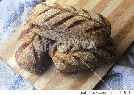 Australian bread on spatula, leaving oven, on rustic wooden background. Traditionally this bread is made with chocolate powder, brown sugar and honey Australian bread on spatula, leaving oven, on rustic wooden background. Traditionally this bread is made with chocolate powder, brown sugar and honey 111361966