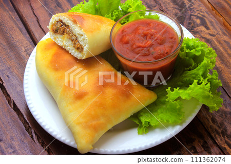 meat esfiha (sfiha) of Arab origin traditionally adapted for the Brazilian cuisine on plate on rustic wooden table 111362074