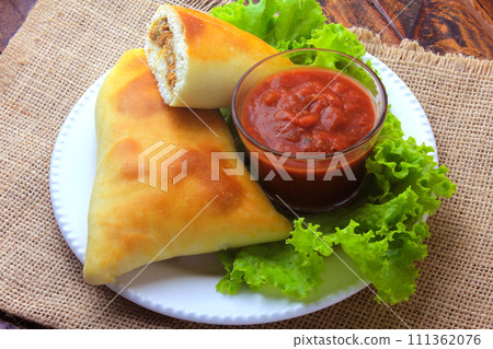 meat esfiha (sfiha) of Arab origin traditionally adapted for the Brazilian cuisine on plate on rustic wooden table meat esfiha (sfiha) of Arab origin traditionally adapted for the Brazilian cuisine on plate on rustic wooden table 111362076